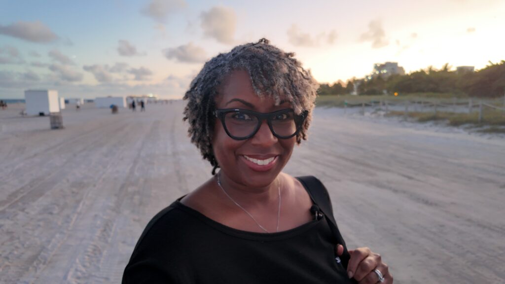 Brandi Carroll smiling on beach at sunset during solo travel journey