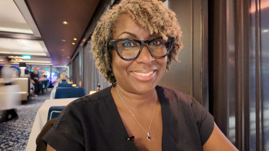 Brandi Carroll smiling at restaurant table, travel advisor and content creator